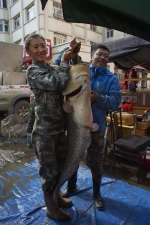 渔民董旗和妻子拿着鲇鱼，照片由虎林市委宣传部提供。 - 新浪黑龙江